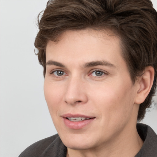 Joyful white young-adult male with medium  brown hair and grey eyes