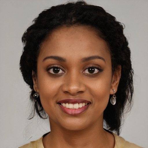 Joyful black young-adult female with long  black hair and brown eyes