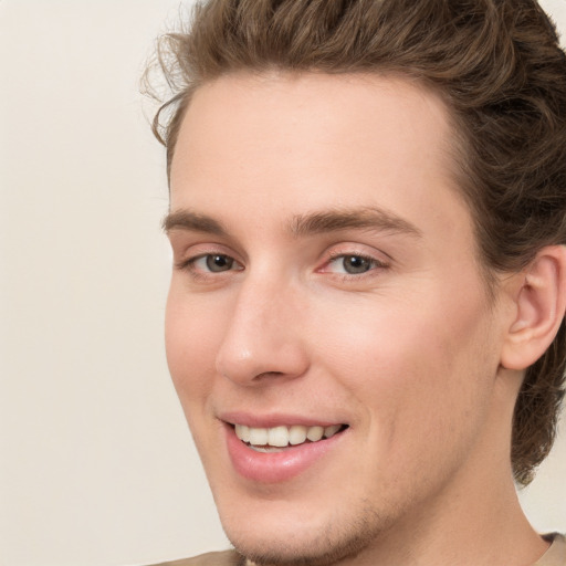 Joyful white young-adult male with medium  brown hair and grey eyes