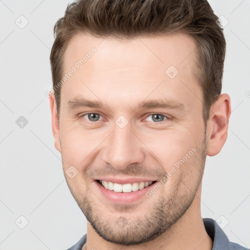 Joyful white young-adult male with short  brown hair and grey eyes