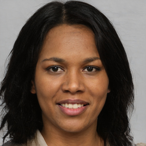 Joyful black young-adult female with long  black hair and brown eyes