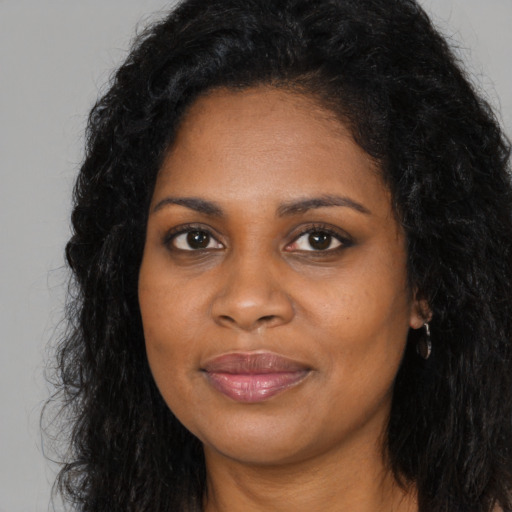 Joyful black young-adult female with long  brown hair and brown eyes