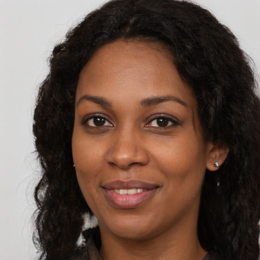 Joyful black young-adult female with long  brown hair and brown eyes