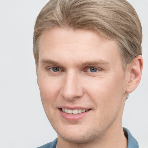 Joyful white young-adult male with short  brown hair and blue eyes