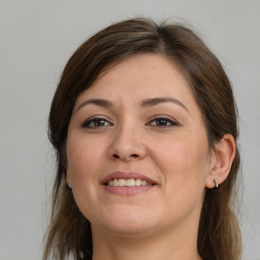 Joyful white young-adult female with long  brown hair and brown eyes