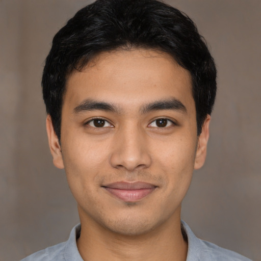 Joyful latino young-adult male with short  black hair and brown eyes