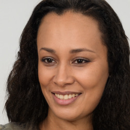 Joyful black young-adult female with long  brown hair and brown eyes