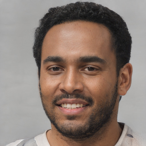 Joyful black young-adult male with short  black hair and brown eyes