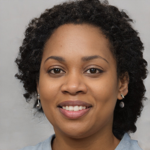 Joyful black young-adult female with long  black hair and brown eyes