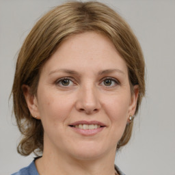 Joyful white adult female with medium  brown hair and grey eyes