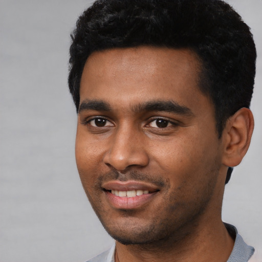 Joyful black young-adult male with short  black hair and brown eyes
