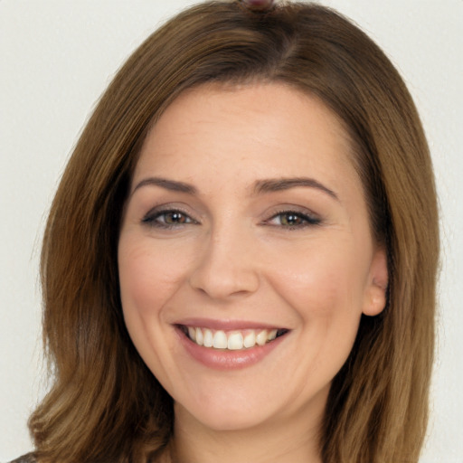 Joyful white young-adult female with long  brown hair and brown eyes