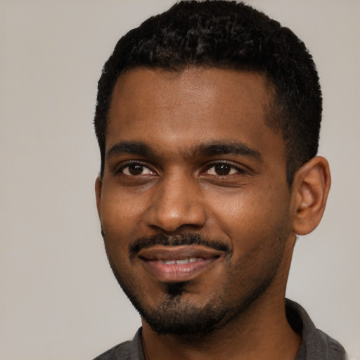 Joyful black young-adult male with short  black hair and brown eyes