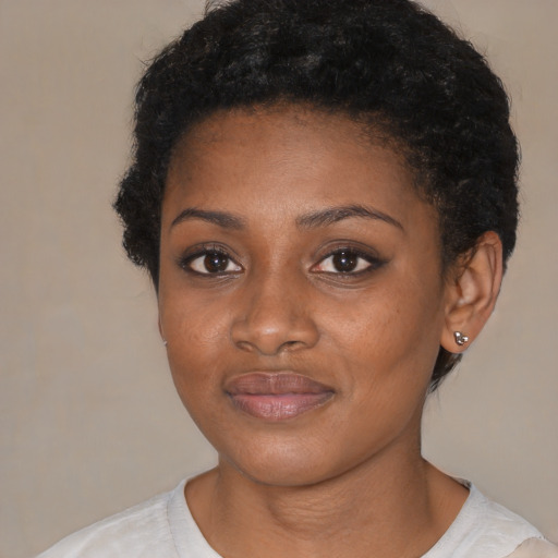 Joyful black young-adult female with short  black hair and brown eyes