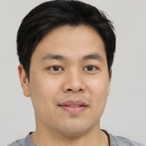 Joyful asian young-adult male with short  brown hair and brown eyes