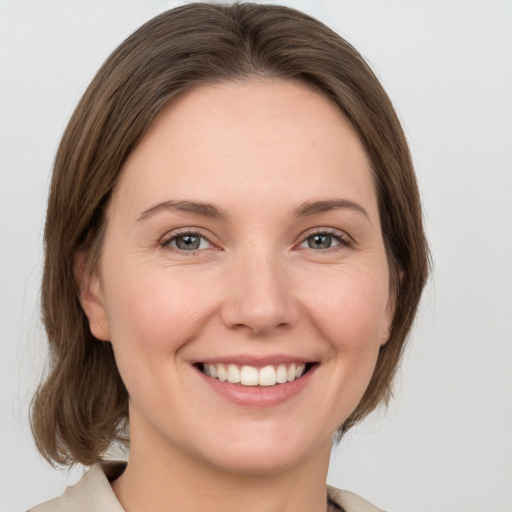 Joyful white young-adult female with medium  brown hair and grey eyes