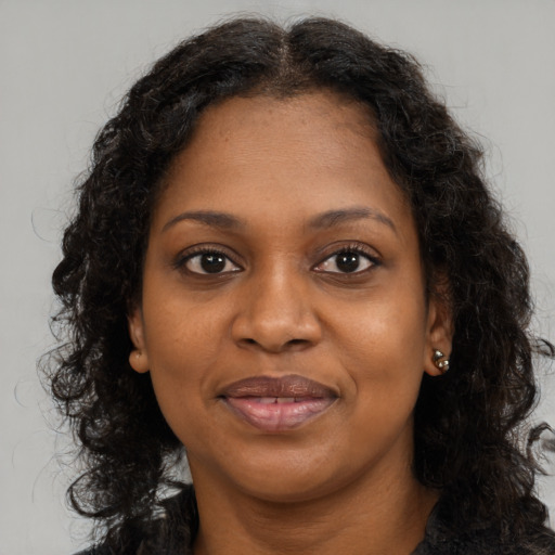 Joyful black young-adult female with long  brown hair and brown eyes