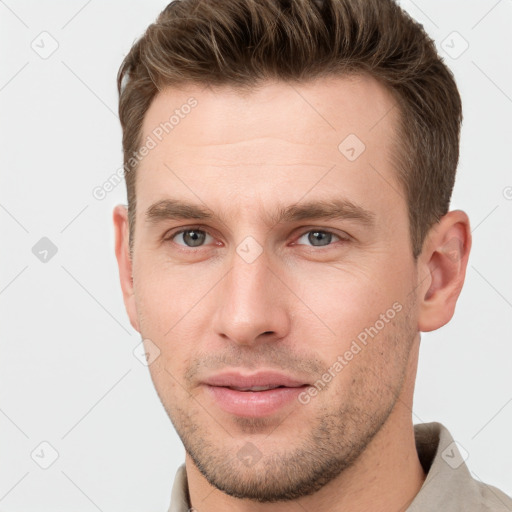 Joyful white young-adult male with short  brown hair and grey eyes