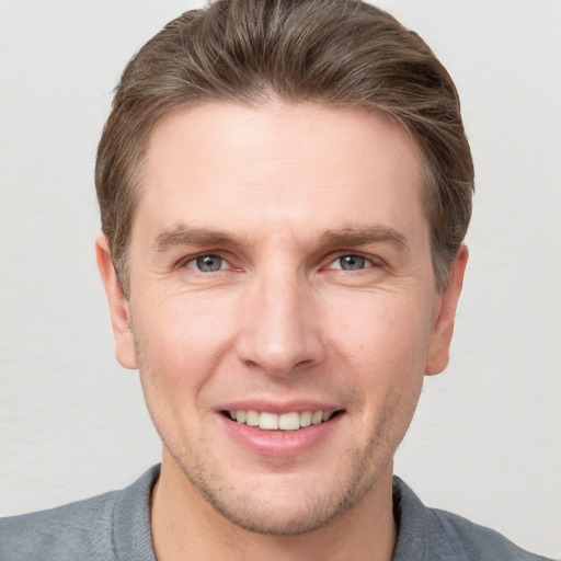 Joyful white young-adult male with short  brown hair and grey eyes