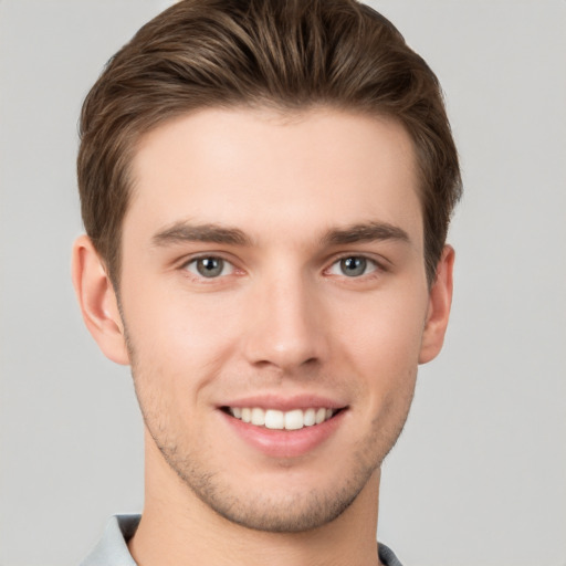 Joyful white young-adult male with short  brown hair and grey eyes