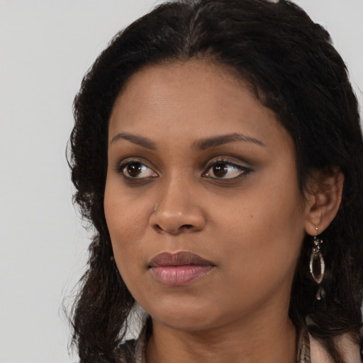 Joyful black young-adult female with long  brown hair and brown eyes