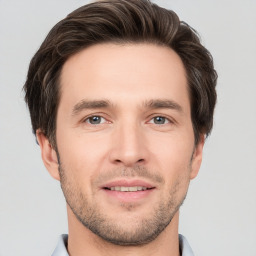 Joyful white young-adult male with short  brown hair and grey eyes