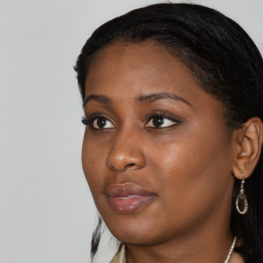 Joyful black young-adult female with long  black hair and brown eyes