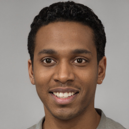 Joyful black young-adult male with short  black hair and brown eyes