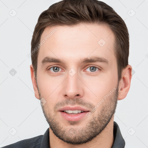 Joyful white young-adult male with short  brown hair and grey eyes