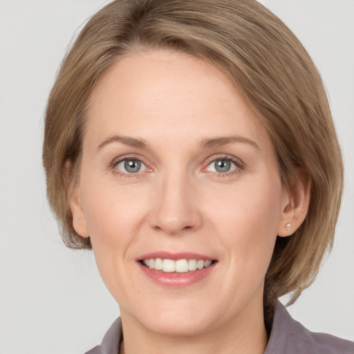 Joyful white adult female with medium  brown hair and grey eyes