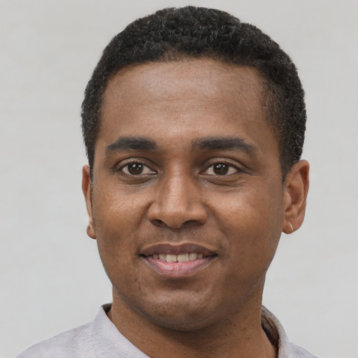 Joyful black young-adult male with short  black hair and brown eyes