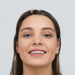 Joyful white young-adult female with long  brown hair and grey eyes