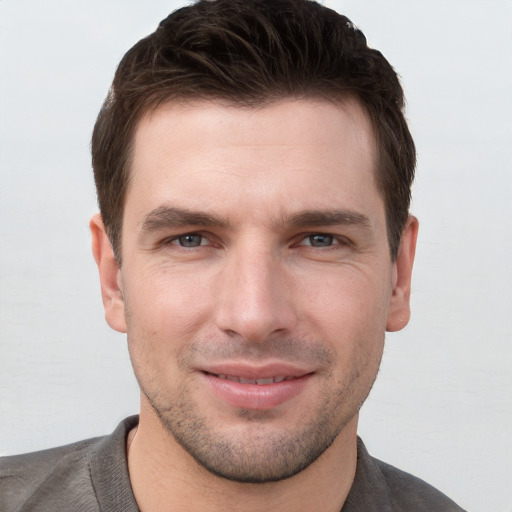 Joyful white young-adult male with short  brown hair and grey eyes