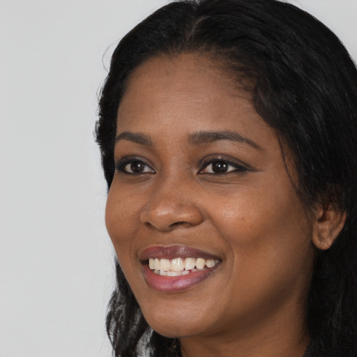 Joyful black young-adult female with long  black hair and brown eyes
