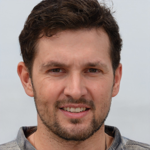 Joyful white adult male with short  brown hair and blue eyes