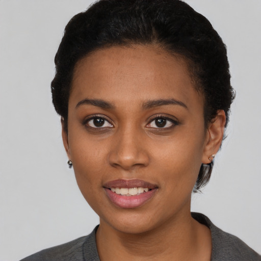 Joyful black young-adult female with short  black hair and brown eyes