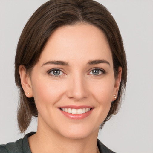 Joyful white young-adult female with medium  brown hair and grey eyes