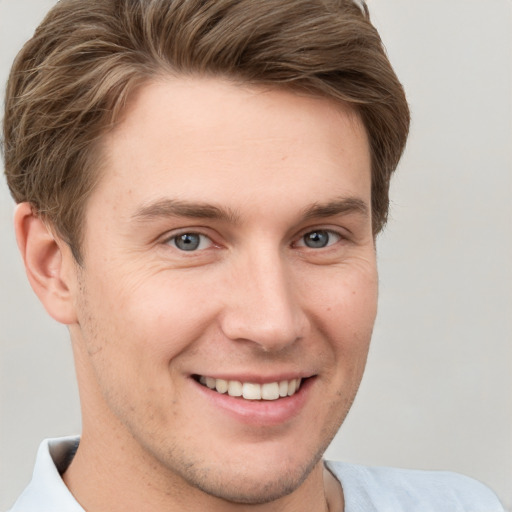 Joyful white young-adult male with short  brown hair and grey eyes