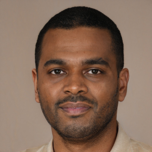 Joyful black young-adult male with short  brown hair and brown eyes