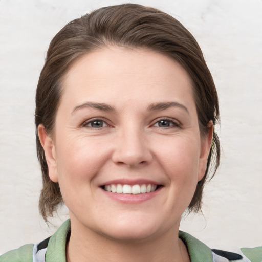 Joyful white young-adult female with medium  brown hair and grey eyes