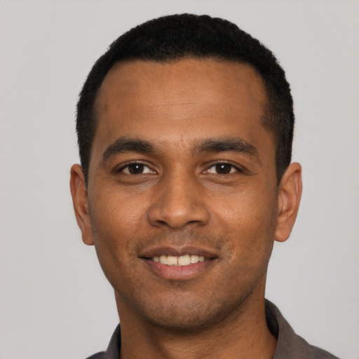 Joyful black young-adult male with short  black hair and brown eyes