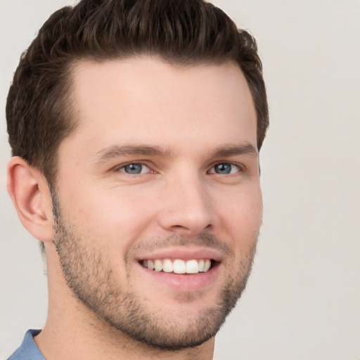 Joyful white young-adult male with short  brown hair and grey eyes