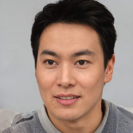 Joyful asian young-adult male with short  black hair and brown eyes