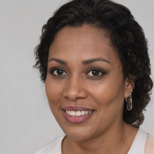 Joyful black young-adult female with long  brown hair and brown eyes