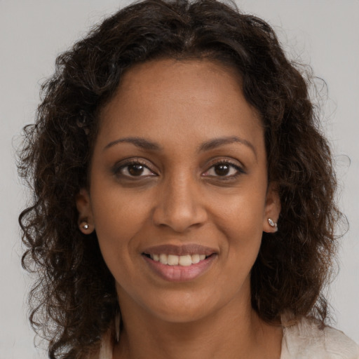 Joyful black young-adult female with long  brown hair and brown eyes