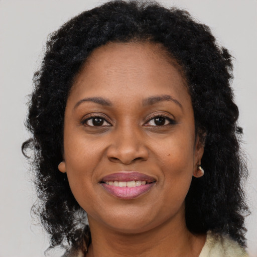 Joyful black young-adult female with long  brown hair and brown eyes