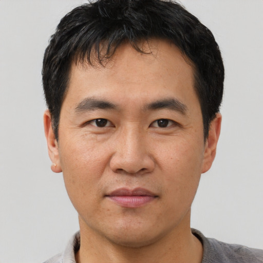 Joyful asian adult male with short  black hair and brown eyes