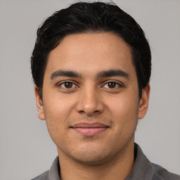 Joyful latino young-adult male with short  black hair and brown eyes