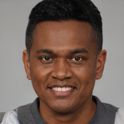 Joyful black young-adult male with short  black hair and brown eyes