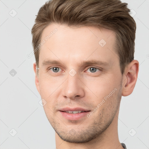 Joyful white young-adult male with short  brown hair and grey eyes